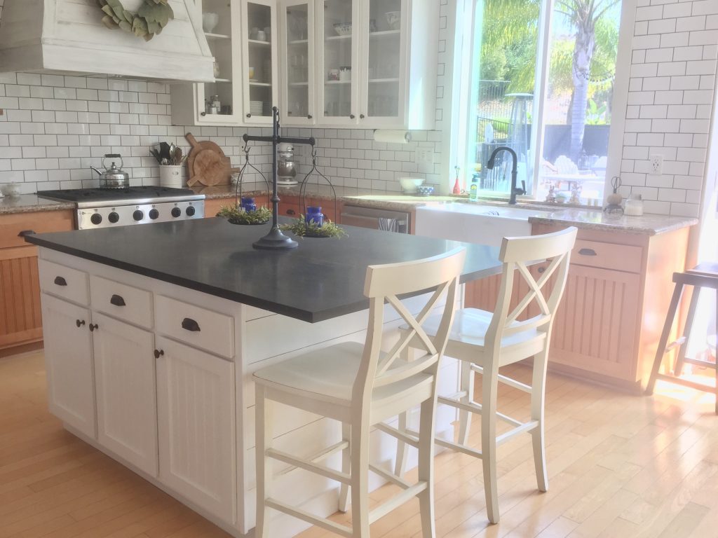 Full view of a kitchen remodel with Frazee white shadow paint, soapstone countertops, white lyra quartz countertops, white subway tile and open shelves.