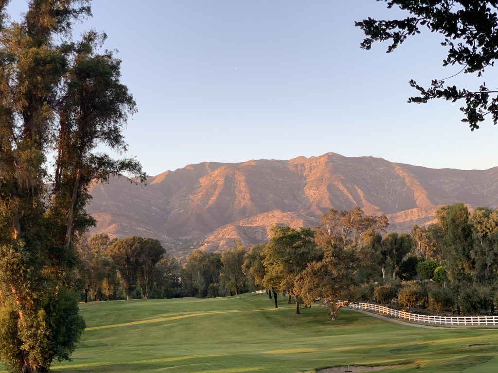 One week California road trip view of green golf course with pink sunset views on hills