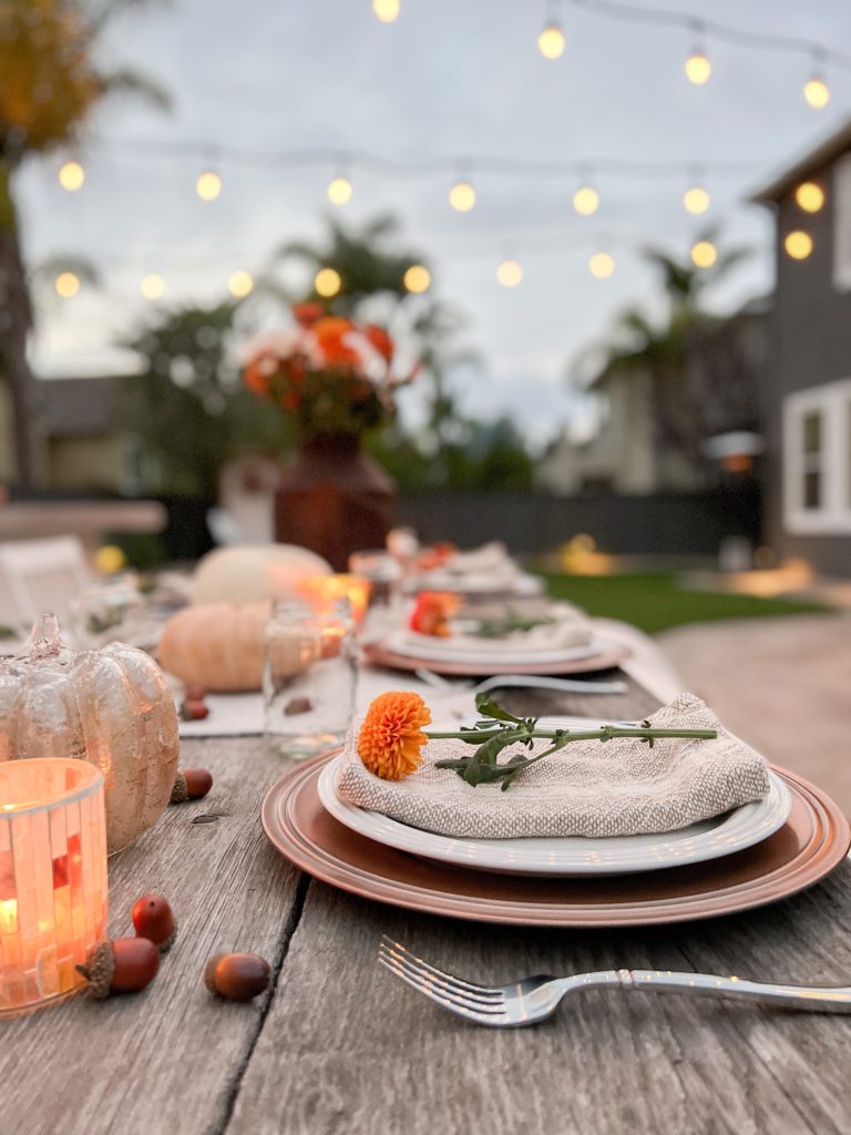 Ideas for a simple and welcoming Friendsgiving Tablescape using vintage decor, pumpkins, flowers, candles, and acorns. Can also be Thanksgiving tablescape ideas - especially an outdoor celebration! #falldecor #thanksgiving #friendsgiving #Thanksgivingtable #Friendsgivingtableideas