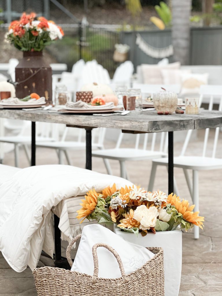 Ideas for a simple and welcoming Friendsgiving Tablescape using vintage decor, pumpkins, flowers, candles, and acorns. Can also be Thanksgiving tablescape ideas - especially an outdoor celebration! Use the Scandia Home down comforter and travel attache for warmth outside! 

#falldecor #thanksgiving #friendsgiving #Thanksgivingtable #Friendsgivingtableideas