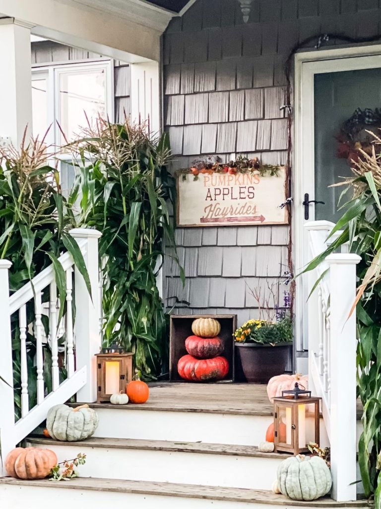 Fall front porch inspiration with pumpkins and gourds on a wooden front porch with stairs