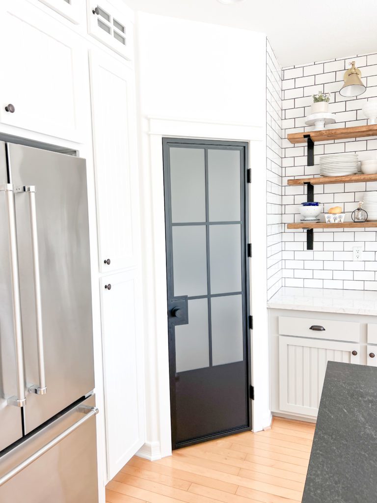 black metal pantry door with white subway tile and soapstone counters 