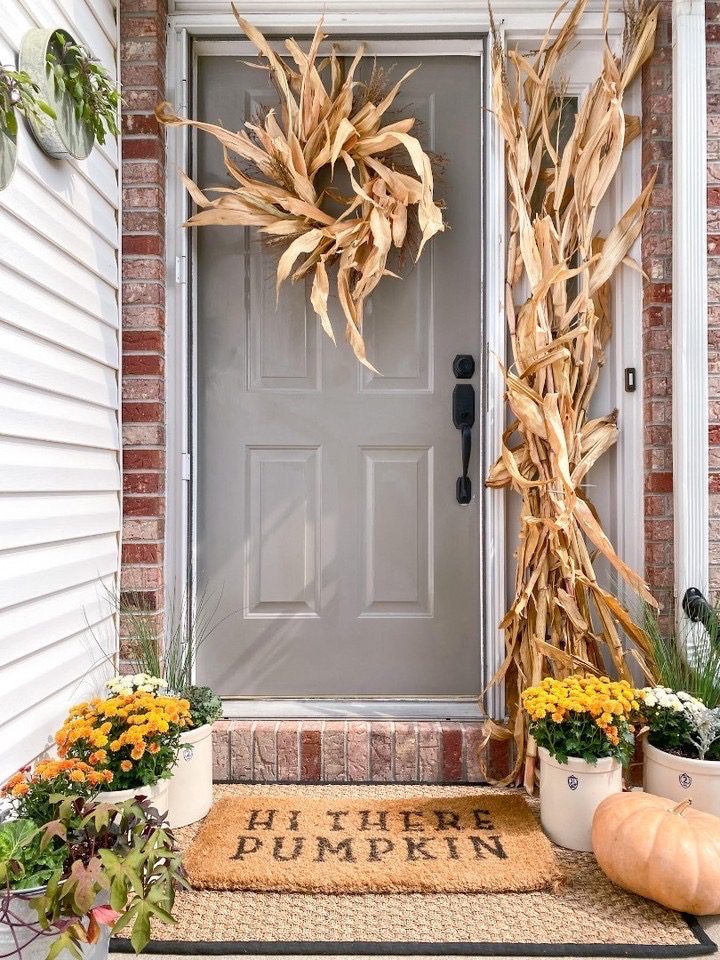 Fall front porch inspiration with corn stalks and pumpkins and mums on a brick front porch