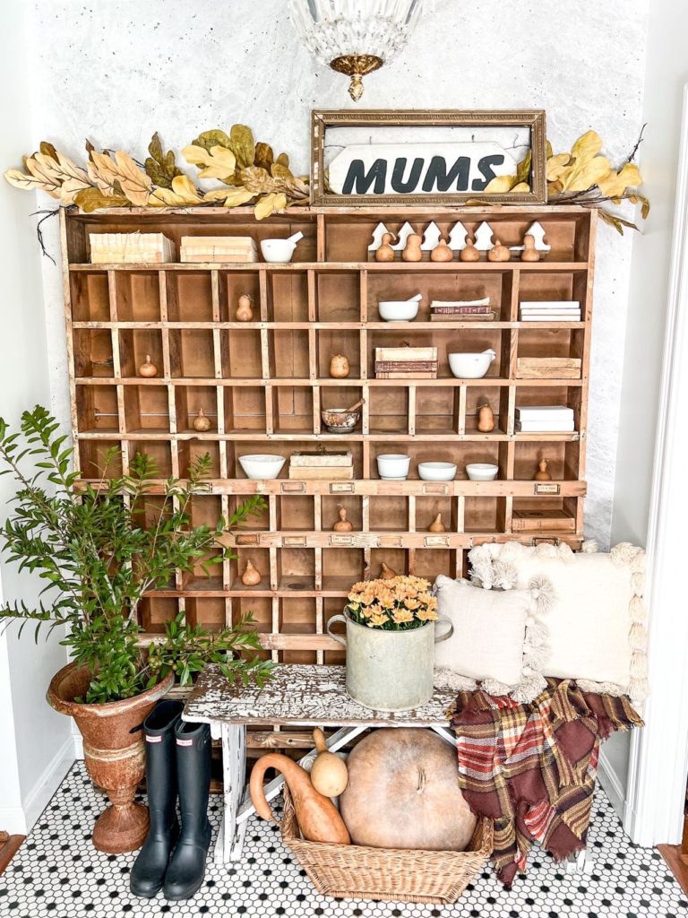 fall front entryway inspiration with gourds and leaves on wooden shelves