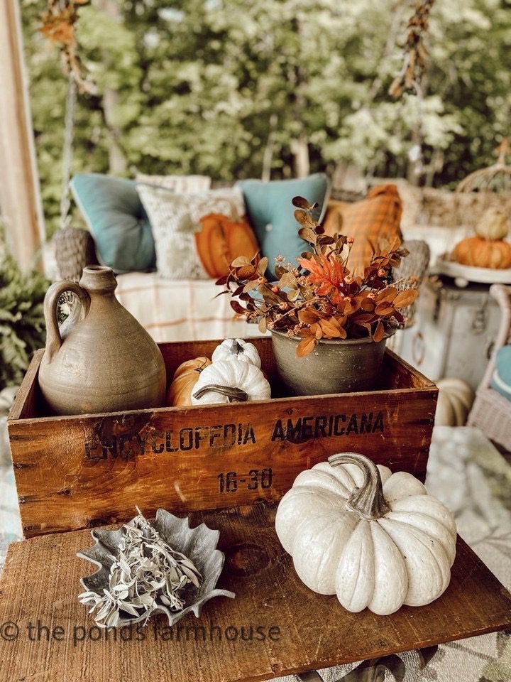 Fall front porch inspiration with a swinging day bed and vintage box with fall leaves and pumpkins
