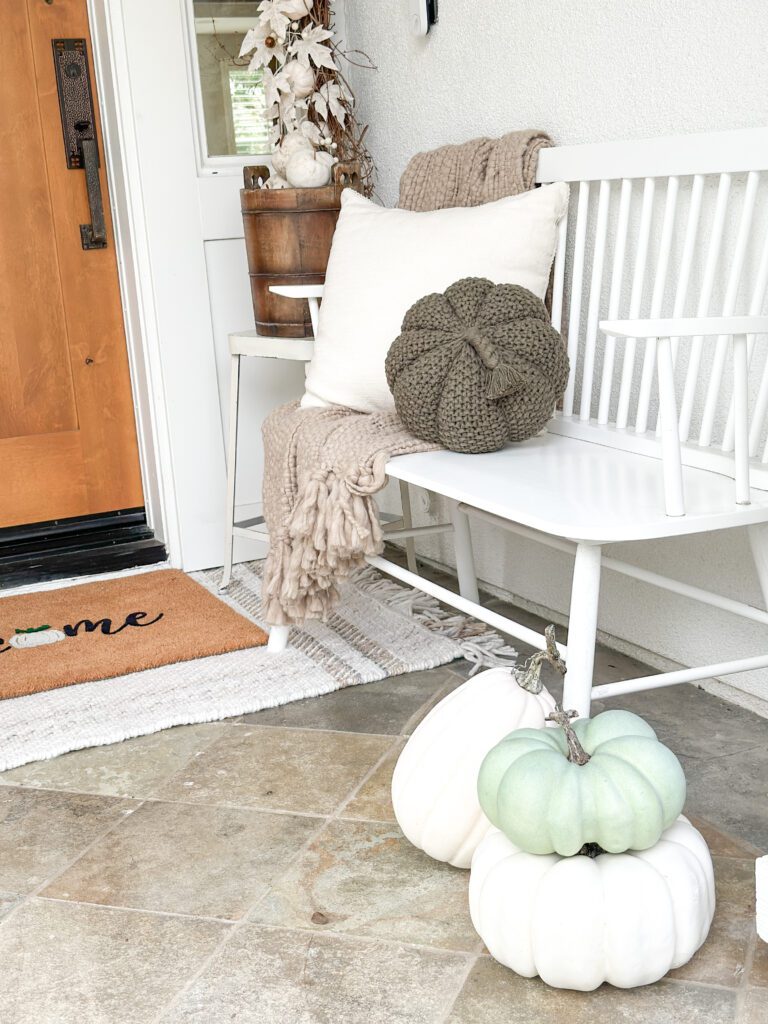 Easy ways to make a cozy fall front porch | Fall decor on the front porch | Making a festive front porch | Decorating for fall on the porch | Using faux pumpkins on the porch | A fall doormat and rug | Fall pillows to decorate your front porch | Faux apples 